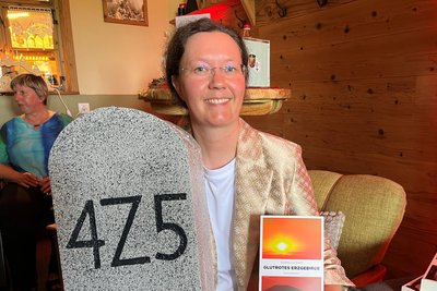 Dieser Stein, dessen Nachbildung Danielle Zinn zeigt, spielt in „Glutrotes Erzgebirge“ eine Rolle. Tatsächlich steht er in Crottendorf an der Zschopaustraße.