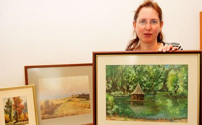 Gabriele Arlt ist Mitarbeiterin des Pfarramtes. Sie zeigt die drei Bilder, die versteigert werden sollen.