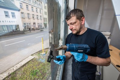 Zu den letzten Arbeiten vor der Eröffnung der neuen Targobank-Filiale in Aue gehört das Entfernen der Schutzfolie von den Fenstern, was Marcel Strobel von der Firma Kötter aus Erfurt übernimmt.