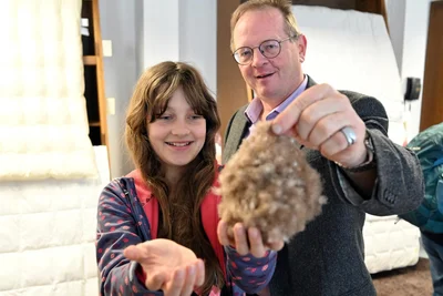 Thomas Uhlmann lässt Lea aus Colmnitz im Schlafmuseum Daunen der Eider Ente anfassen. Sie sind als Bündel federleicht und haben zugleich ein hohes Klettverhalten.