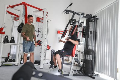 Lagerlogistik-Mitarbeiter André Steinbach (rechts) trainiert in Pausenzeiten im Fitnessbereich der Firma am Butterfly, eines von insgesamt Geräten, um für die Arbeit Kraft zu tanken.