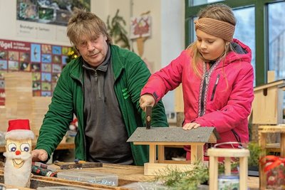 Michelle deckt in der Holzwerkstatt unter der sachkundigen Anleitung von Andreas Borowski das Daches eines Futterhauses mit Dachpappe. 