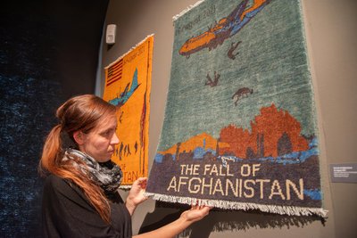 Museumsleiterin Tina Reitz an einem der afghanischen Kriegsteppiche in der Sonderausstellung auf Schloss Voigtsberg.