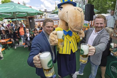 Die Schausteller Felix Hickmann (links) und Rico Illgen genießen zusammen mit Maskottchen Käti ein frisch gezapftes Bier.