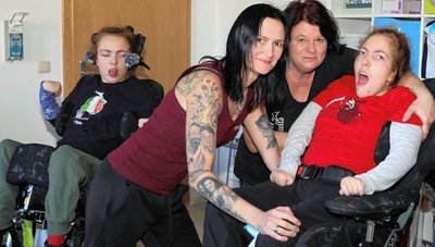 Mutter Stephanie Dittrich-Schulz (vorn links) und Heike Wagner setzen Fanny nach einer Therapiestunde in den Rolli. Im Hintergrund wartet Stella auf ihre Schwester. 
