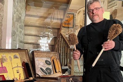 Das Bürsten- und Heimatmuseum in Schönheide hat das Festjahr 200 Jahre Bürstenindustrie zum Anlass für eine Sonderausstellung genommen. Museumsleiter Andreas Schubert steht vor Koffern, die eine Auswahl an Bürsten zeigen, wie sie früher vom Bürstenmann zu Kunden direkt ins Haus gebracht wurden. 