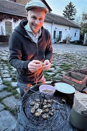 Schneckenzüchter Andreas Gugumuck streut Gewürze in die Schneckenhäuser, bevor sie auf den Grill kommen.