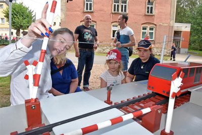 Allyah-Jolina Naumann vom Präventionsteam der Bundesbahn erklärt Louise (links) und Lotta zum Ortsfest in Kleinschirma die Gefahren einer Oberleitung und die Funktionsweise eines beschranken Bahnübergangs.