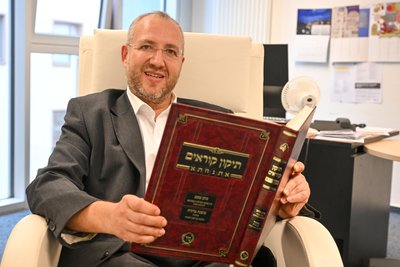 Michael Jedwabny in seinem Büro. Das Buch in seinen Händen hilft, die Tora, die ohne Satzzeichen geschrieben ist, zu verstehen. Da er die Tora aber fast auswendig kennt, braucht er das Buch nur sehr selten.