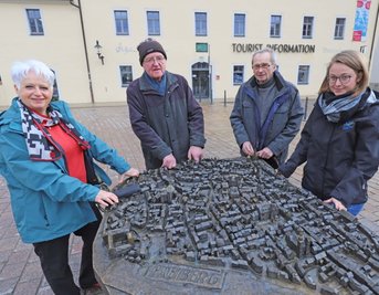 Die Stadtführer Ellen Köstner (von links), Gerhard Haubold, Klaus Kempe und die Tourismusmitarbeiterin Janine Preißler am Freiberger Stadtmodell auf dem Schloßplatz.