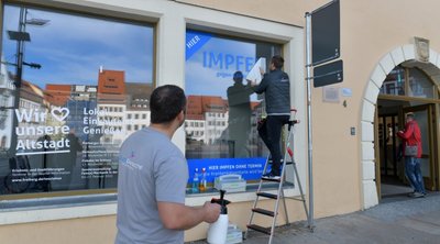 Sebastian und Robert Liebscher (von links) von der Firma Druckgemacht gestalteten am Montag das Schaufenster. 