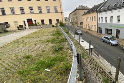 Teil des Problems, Teil von dessen Lösung: In das Erdreich hinter der Mauer zur Bushaltestelle wird bald tief eingegriffen. Die jetzt schon gesperrten Parkplätze gibt es nach den Arbeiten nicht mehr.