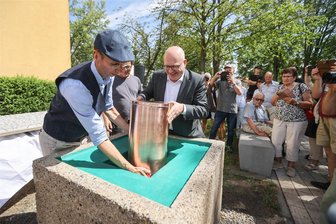 50 Jahre Heckert: Geschenke für ein Chemnitzer Wohngebiet - Norbert Engst vom Chemnitzer Geschichtsverein (links) und Oberbürgermeister Sven Schulze beim Versenken der neuen Zeitkapsel im Grundstein für das Heckert-Gebiet. Der Stein wird mit einer Platte verschlossen und steht nun am Wenzel-Verner-Platz.