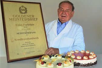 50 Jahre Konditormeister in Reichenbach und immer noch aktiv - Konditormeister Klaus Forbriger mit seinem Goldenen Meisterbrief und zwei leckeren Torten aus der Produktion von Forbriger Backwaren: Gin und Blutorange. 