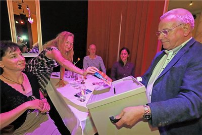 Andreas Schwinger (r.) sammelt mit der Wahlurne die Stimmzettel des Publikums ein. 