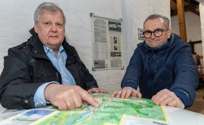 Sven Mues (links) und Michael Lienemann in der Erik-von-Trützschler-Box der Oldtimer-Garage im früheren Güterschuppen am Bahnhof Falkenstein. Die Fahrzeugboxen tragen die Namen berühmter Autorennfahrer. Vor sich haben die Organisatoren die Karte mit dem Kurs für die Premiere der Vogtland-Rundfahrt am 4. Juni. 
