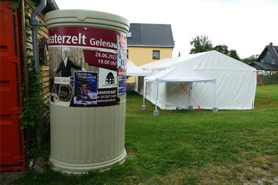Eine als Litfaßsäule getarnte Regenwassertonne zeugt noch von den Puppentheatertagen des vergangenen Jahres, kündigt aber zugleich die bevorstehenden Auftritte an.