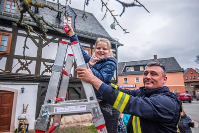 Emma Trülzsch hängte eins der vorbereiteten Eier in den Apfelbaum. Dabei half ihr Wehrleiter Mario Voigt.