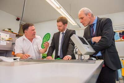 Firmenchef Hartmut Funke (links) erklärt Ministerpräsident Michael Kretschmer und Eibenstocks Bürgermeister Uwe Staab  die Funktionsweise der innovativen Sohle.