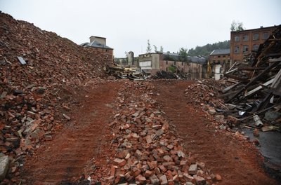 Meterhohe Berge Bauschutt, das bleibt von der alten Industriebrache übrig. Die Gebäudeteile zum Bahnhof hin stehen noch und schirmen die Baustelle ab. 