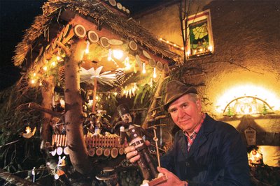 Schnitzmeister Harry Schmidt aus Bermsgrün vor seinem Haus in Bermsgrün mit einem seiner markanten Astmännlein in der Hand. Schmidt starb 2003.