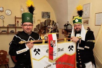 500-jähriges Bestehen: Was Kurt Biedenkopf mit der Bergknappschaft Scheibenberg verbindet - Michael Bleyl und Ronny Graupner (r.) von der Bergknapp- und Brüderschaft Oberscheibe/Scheibenberg präsentieren in den Vereinsräumen, die sich in Scheibenberg am Markt 4 befinden, die Knappschaftsfahne.