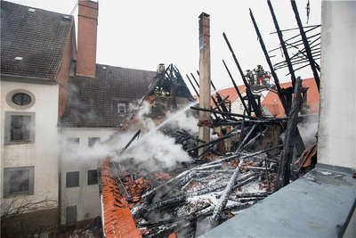 Rauchschwaden wabern durch die Luft: Feuerwehrmänner löschen im Dachstuhl, vom dem nur ein Gerippe übrig blieb, Glutnester.