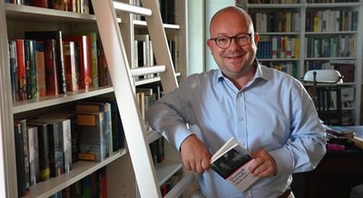 Frank Müller-Rosentritt am heimischen Bücherregal. 