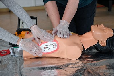 Ausbilderinnen demonstrieren an einer Reanimationspuppe die Wiederbelebung mit Einsatz eines Defibrillators.