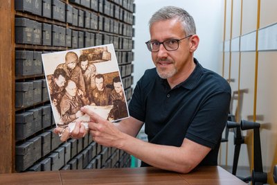 Ralf Härtel zeigt im Stadtarchiv Mittweida ein reproduziertes Foto, das Alexander Balter (2. v. l.) am Funkgerät zeigt. Das Bild erschien Anfang Mai 1945 in zwei US-Tageszeitungen.