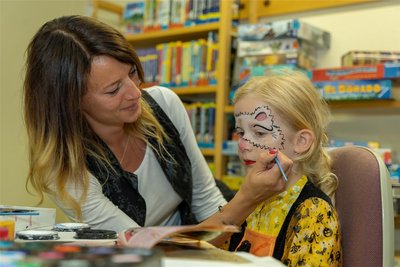 Marie lässt sich in der Bibliothek von Ulrike Döhler von der Kita Sonnenschein ein Katzengesicht aufmalen.