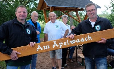 Vereinschef Ingo Claus (rechts) hat mit Christian Meyer (links) das Schild für den Rastplatz "Am Äpelwaach" angebracht. Wolfgang Winkler (3. v. l.) und Klaus Böhm (2. v. l.) haben sich um die mit Musik der Oelsnitzer Blasmusikanten hinterlegten QR-Codes gekümmert. 
