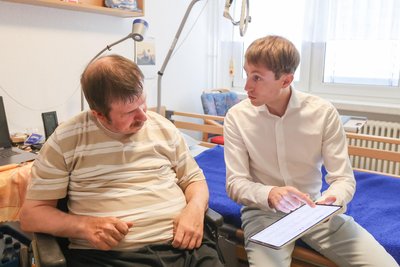 Professor Tom Schaal erklärt Heimbewohner Kamillo Ernst, welche Daten mit dem Neteera-System aufgezeichnet werden.