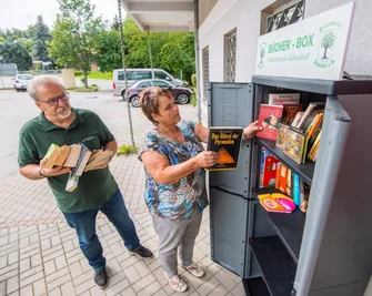 Der Heimatverein freut sich, dass der Bücherschrank auf dem Parkplatz des Nahkaufs gut angenommen wird. Die Vereinsmitglieder Christa Götz und Herbert Pchalek befüllen ihn. 