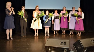 Mitwirkende an der Vogtlandsaga präsentierten sich in der Vogtlandhalle Greiz. Von links: Drehbuchautorin Sabine Maria Schoeneich, Melanie Riedel (Dorothea), Stefanie Hertel (Ella) sowie die musikalischen Mitstreiter Emily Alnajjar und die Grünbacher Folkloristen.