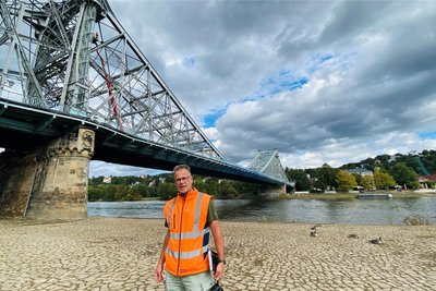 Jens Gorgius von der Stadtverwaltung Dresden vor der Loschwitzer Brücke, links im Hintergrund die Prüfingenieure auf der Hebebühne.