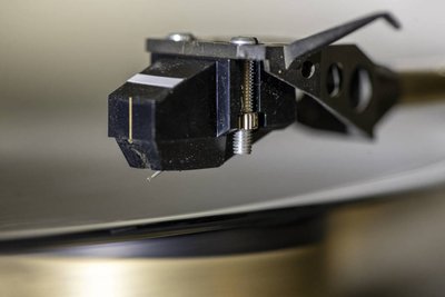 Makrofoto eines Schallplatten-Tonabnehmers: Man ahnt, wie winzig die Nadelspitze ist - und dass Staub da wie Geröll in der Rille wirkt! 