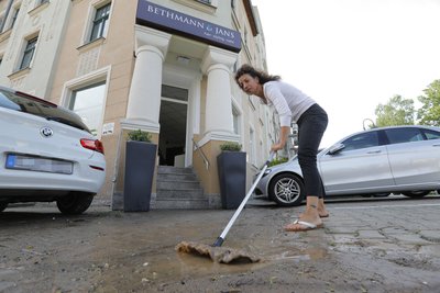 Silke Bethmann kehrt Wasser und Schlamm vor ihrem Laden auf dem Kaßberg weg.