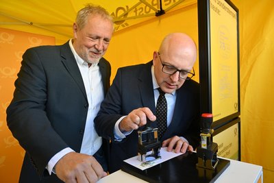 Bernd Meyer von der Deutschen Post assistiert OB Sven Schulze beim Stempeln der ersten Marke.