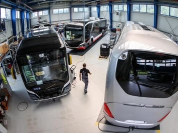 Ein Mitarbeiter geht durch eine Halle mit Elektrobussen von MAN. 