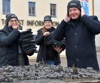Luise Ulbricht (links) hat eine "Mütze für mehr Miteinander" kreiert. Am Dienstag übergab sie 50 Stück davon an Babett Erler von der Tourist-Information. OB Sven Krüger (parteilos) probierte eine auf. 
