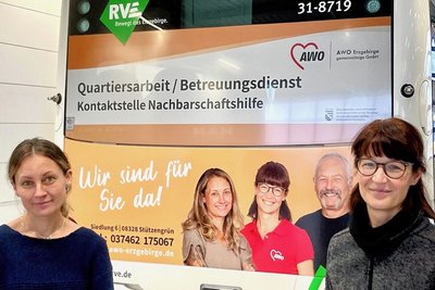 Kerstin Klöppel (r.) und Franziska Hänel von der Awo Erzgebirge werben auf einem Bus für ein besonderes Angebot des Quartiersbüros in Stützengrün. 