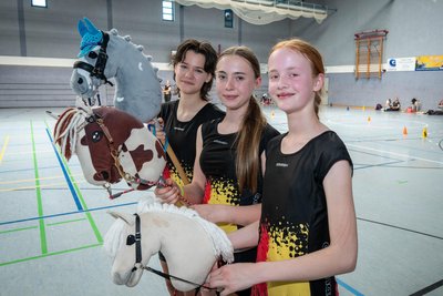 Die Steckenpferde sind je nach Disziplin etwas unterschiedlich gestaltet. Lina (von links), Aline und Isabelle zeigen Dressur-, Western- und Springpferd.