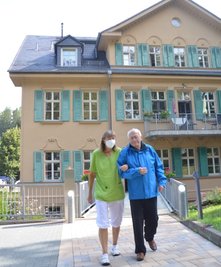 10 Jahre Hospiz "Ellen Gorlow" in Oederan: Pflegedienstleiterin Angela Kräher geht mit Bewohner Eberhard Schuster im Park vor der klassizistischen Villa spazieren. Am 10. September wird es ein Fest geben. 