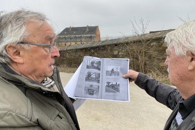 Mit Blick aufs Gutshaus und die letzten Mauerreste der Gutseinfriedung: Günter Hofmann (links) und Wolf-Dieter Seifert diskutieren anhand von Aktenkopien aus dem Sächsischem Staatsarchiv den Tathergang.