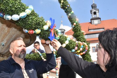 Cornelia und Mike Naumann bringen einen Osterhasen als Brunnenschmuck an.
