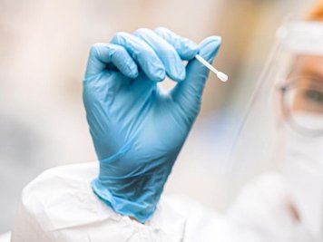 Eine medizinische Mitarbeiterin hält einen Tupfer für einen Abstrich für einen Corona-Test in der Hand.