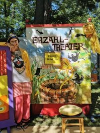 Unterm Kirschbaum wartet Biggi mit ihrem Erzähltheater auf Kinder.