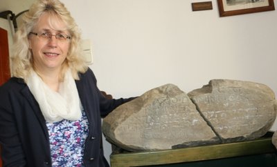 Die Reuther Pfarrerin Sabine Stepper zeigt den Stein mit dem Bibelspruch. Er stammt vom Wohnhaus des gelehrten Bauern. 