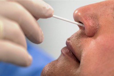 Ein speziell geschulter Mitarbeiter des Maschinenbauers Harro Höfliger führt bei einem Kollegen in einem zum Testraum umfunktionierten Produktionsreinraum einen Corona-Schnelltest durch. 